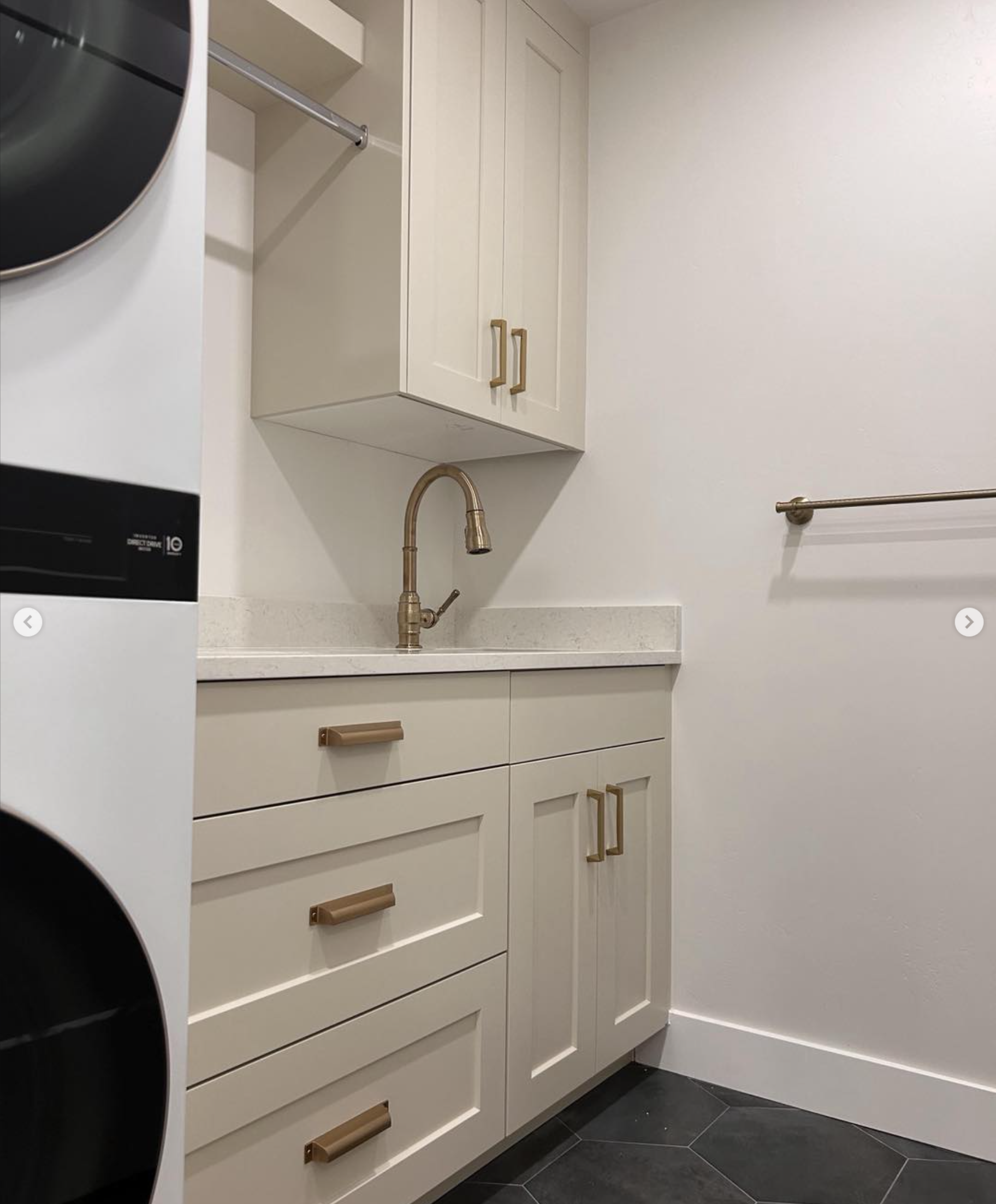custom-laundry-room-cabinets-sink-draper-utah | Pro-Worx Construction Laundry area with a stacked washer/dryer, white cabinets with gold handles, brass faucet, and a towel rack on the wall.