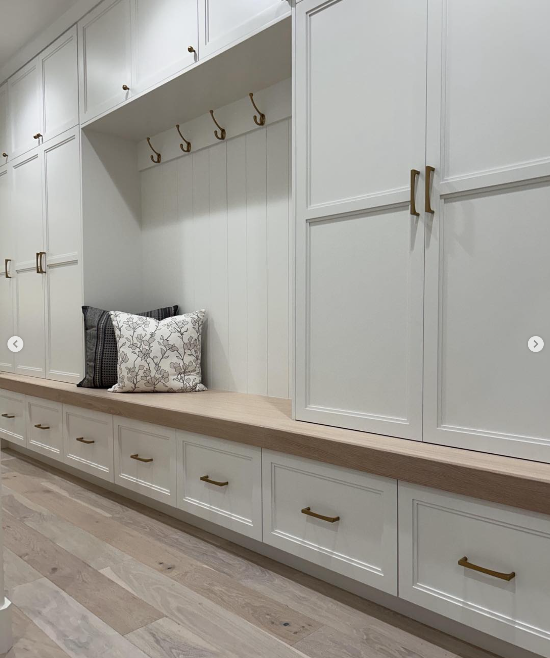 custom-mudroom-built-in-bench-lockers-salt-lake-city-utah | Pro-Worx Construction White wall of cabinetry with beadboard doors and brass pulls, a light wooden countertop, and built-in seating with patterned cushions.